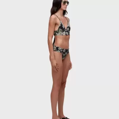 Mulher com biquíni preto com flores, sandálias pretas e óculos de sol verde em fundo branco