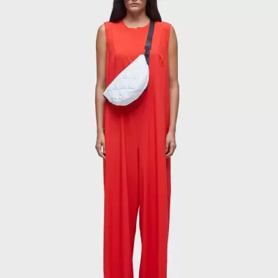 Mulher com macacão vermelho, pochete branca acolchoada e óculos escuros