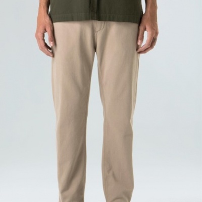 Pessoa com calças bege, camisa verde escura e ténis pretos