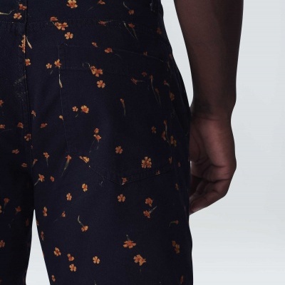 Calções azuis com flores laranja usados por pessoa com pele escura e camisola verde