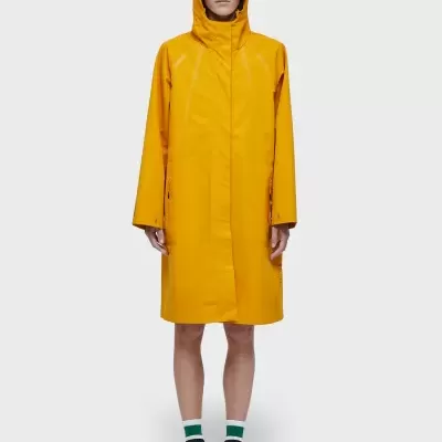 Casaco impermeável amarelo de frente com capucho e sapatos brancos