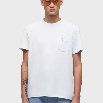 Modelo com camiseta branca de algodão com bolso e texto azul claro, óculos de sol laranja e calças azul claro