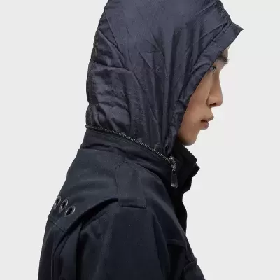 Pessoa de perfil a usar casaco azul escuro com capuz amovível em nylon