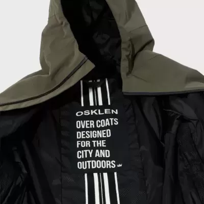 Casaco com capuz verde-oliva com interior preto e etiqueta preta com texto branco