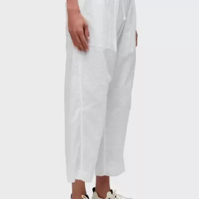 Calças brancas com padrão perfurado e ténis brancos com detalhes pretos