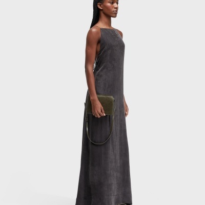 Mulher com vestido cinza escuro, sandálias brancas e bolsa verde escura.