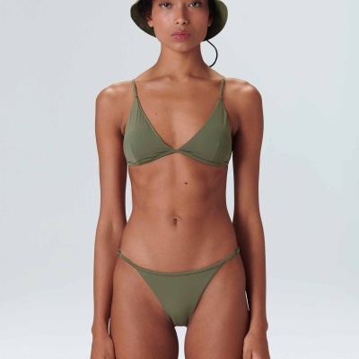 Mulher a usar fato de banho verde e chapéu pescador verde sobre fundo cinzento