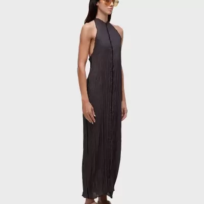 Vestido comprido preto texturizado com sandálias bege e óculos de sol amarelados.