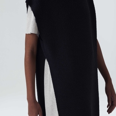 Colete longo preto felpudo sobre túnica branca de manga curta