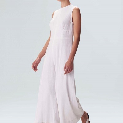 Mulher usando macacão branco sem mangas e sandálias brancas em fundo branco