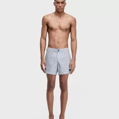 Homem de pé a usar fato de banho curto de riscas brancas e cinzentas