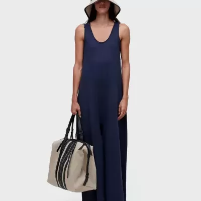 Pessoa com fato-macaco azul e chapéu creme segura mala creme com riscas pretas