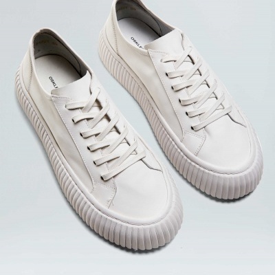 Sapatilhas brancas com sola grossa e textura distinta