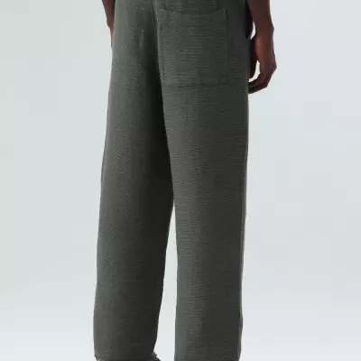 Calças largas cinza escuro com padrão fino, vista traseira, usadas por modelo com sapatilhas pretas