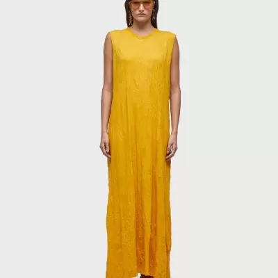 Vestido comprido amarelo com padrão subtil e óculos de sol