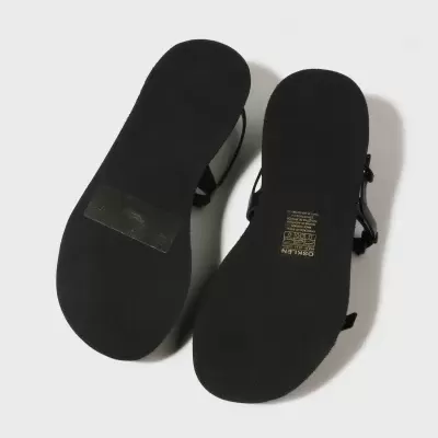 Par de sandálias pretas com sola lisa e texto na sola