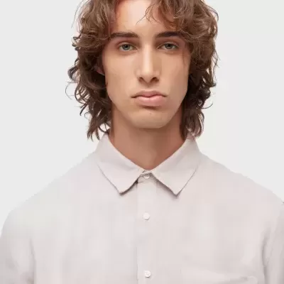 Homem com camisa creme de tecido leve com gola clássica e bolso no peito