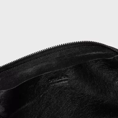 Interior de bolsa ou carteira preta em couro com fecho de correr preto e nome gravado