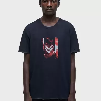 Camiseta preta com estampa vermelha e branca ao centro, usada por modelo masculino.