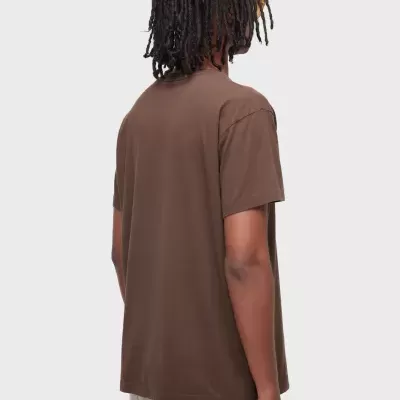 Pessoa de costas com t-shirt castanha e calças claras