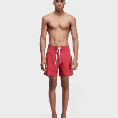 Homem com calções de banho vermelhos e cordão branco