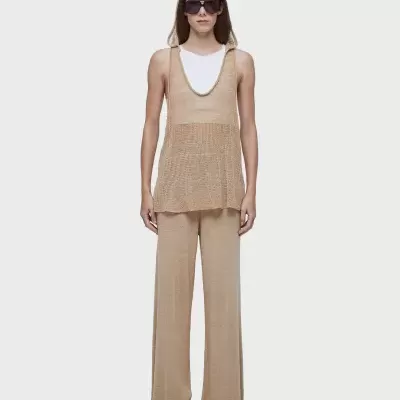 Mulher de túnica e calças bege com t-shirt branca e óculos escuros