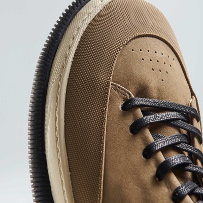 ténis castanho com atacadores pretos e sola preta com borda bege