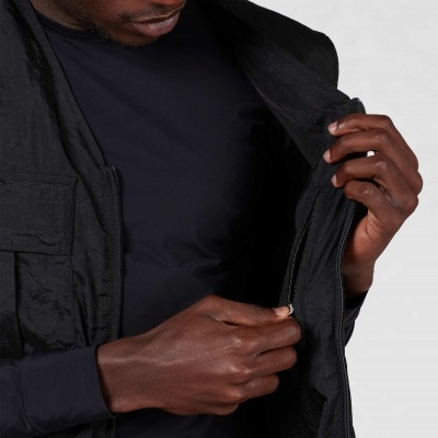 Pessoa a fechar o fecho de um casaco ou colete preto com tecido liso e interior respirável