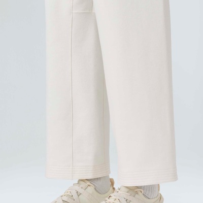 Sapatilhas esportivas bege com sola texturizada usadas com meias brancas e calças largas claras