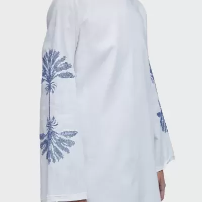 Vestido branco comprido com estampas azuis de palmeiras nas mangas.