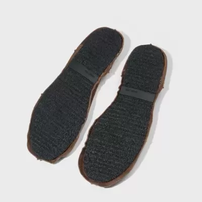 Solas de sapatos castanhas com base preta e texto OSKLEN.