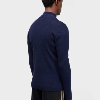 Homem de costas com camisola azul escuro e calças pretas com riscas bege