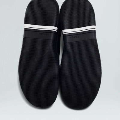 Solados pretos com faixa branca sobre fundo cinzento