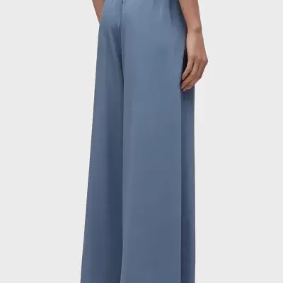 Calças largas de tecido azul claro com cintura franzida, vista traseira