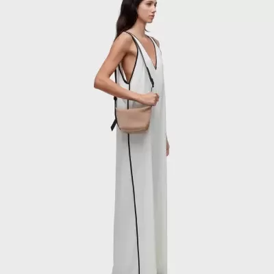 Mulher com vestido comprido branco e bolsa bege