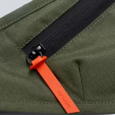 Fecho de correr preto com puxador laranja em bolsa verde