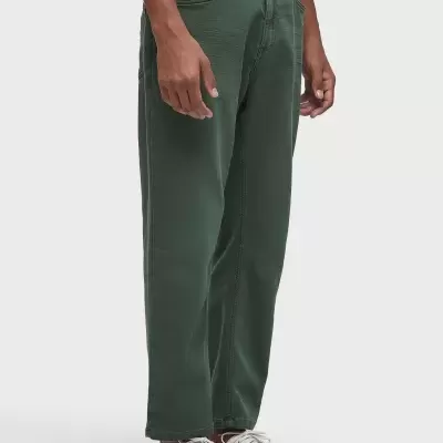 Calças verdes de tecido liso usadas por modelo com t-shirt azul e ténis brancos