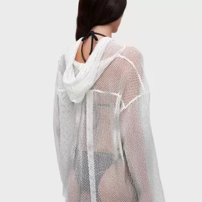 Peça de roupa branca de malha transparente com capuz no corpo de uma mulher vista de costas