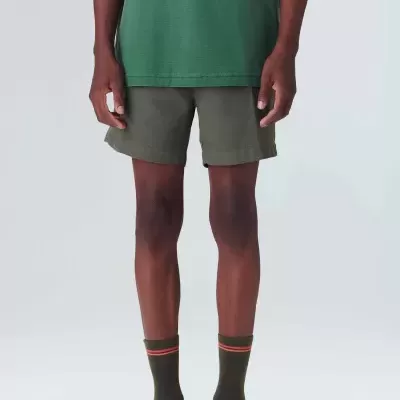 Homem de verde escuro com calções cinza escuro, meias verdes com riscas laranjas, sapatos pretos