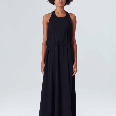 Modelo a usar vestido longo preto sem mangas com sapatos brancos em fundo branco