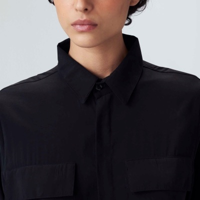 Camisa preta com colarinho e bolsos no peito, usada por mulher com cabelo curto