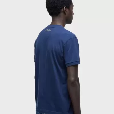 Homem de costas com t-shirt azul escuro e jeans azul claro.