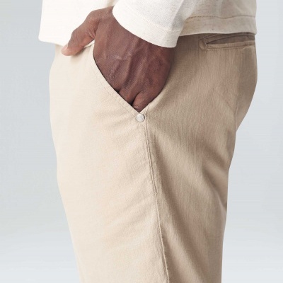 Calções bege com bolso e botão usados por pessoa com camiseta creme.