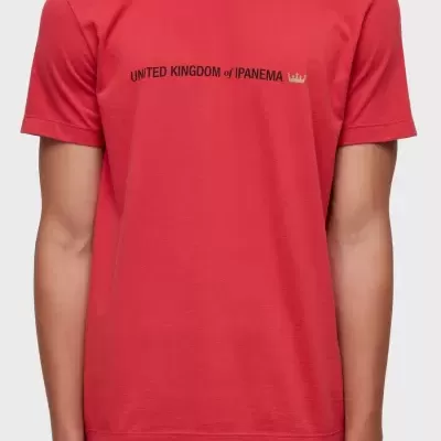 T-shirt vermelha com texto UNITED KINGDOM of IPANEMA e coroa amarela usada com calções riscas.