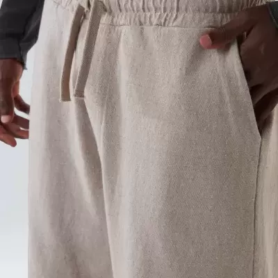 Calças largas de linho bege com cintura elástica e cordão ajustável, combinadas com camisa preta de manga comprida