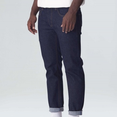 Calças de ganga azuis escuras com bainha virada usadas com camisola branca e sapatilhas brancas