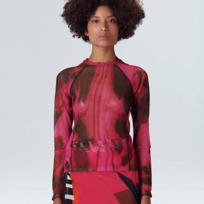 Blusa feminina transparente vermelha com padrão castanho e saia vermelha geométrica.