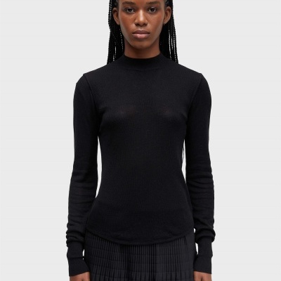 Mulher veste camisola preta de malha fina com gola alta e saia preta plissada