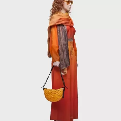 Mulher com vestido laranja e bolsa amarela com padrão de trama