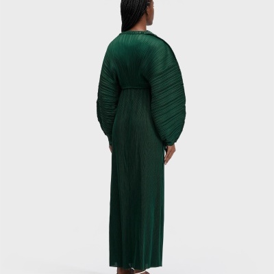 Vestido longo verde escuro com mangas bufantes e sandálias brancas vistas de costas.